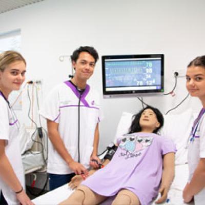 Student Nurses standing around a patient in a hospital bed