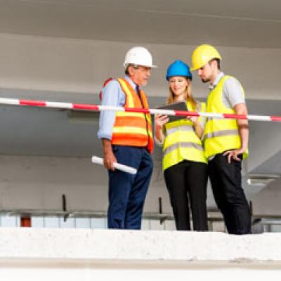 Construction workers standing on a bridge looking at plans