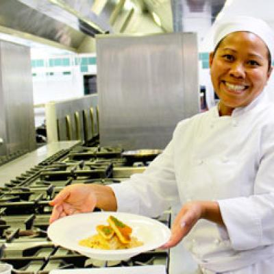 Commercial Cookery student smiling with a beautifully presented plate of food