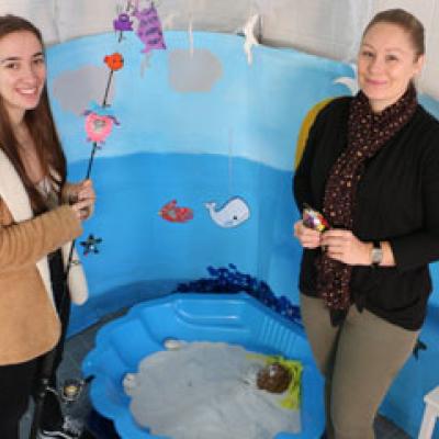 Two Education Assistants standing with some homemade children's activities