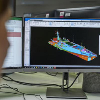 Engineer with a CAD drawing of a large ship on their screen