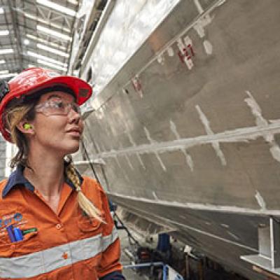 Engineer standing in front of a large ship being built