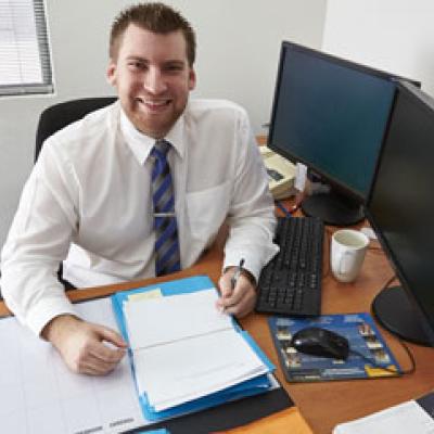 Manager looking man sitting at a computer with a file of paperwork