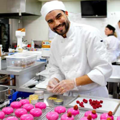 Patisserie student in the kitchen making glazed pink pastries