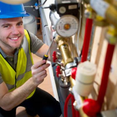 Plumber posing with gas pipes and valve