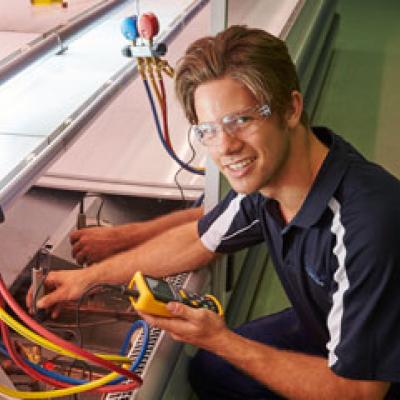 Refrigeration mechanic repairing a large industrial fridge