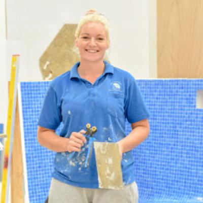 Tiler standing in front of a blue tiled wall