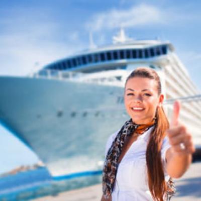 Lady giving a thumbs up in front of a cruise liner