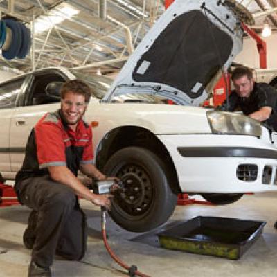 Two mechanics servicing a vehicle