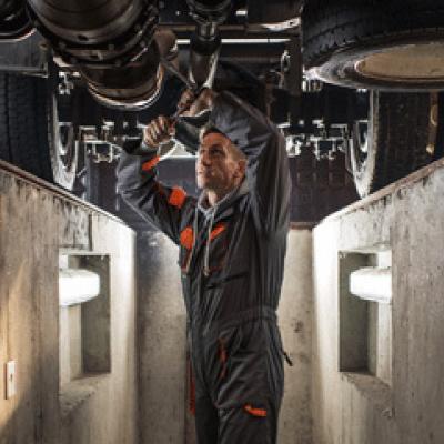 Mechanic working under a large truck in a pit