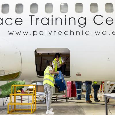 Two students loading baggage into an airplane 