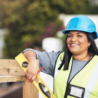 Female in high vis vest and hard hat posing next to a wood structure