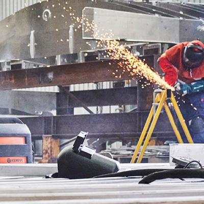 a person in uniform and safety mask welding at a job site