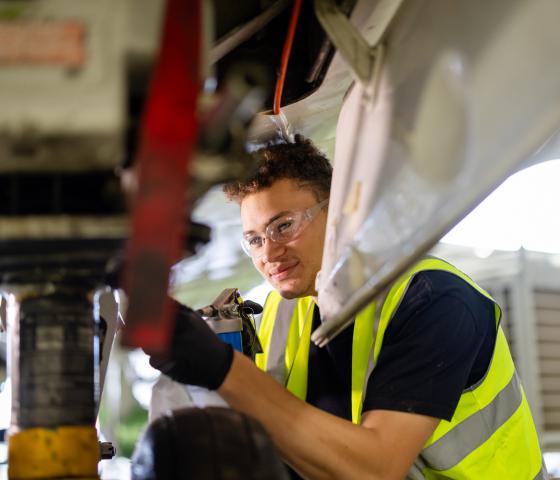 A pilot student in high vis underneath an airplane