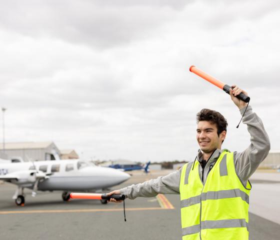 A student on the tarmac directing planes