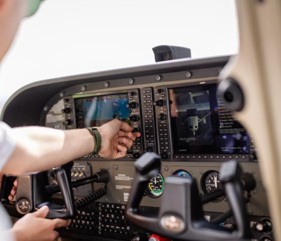 A pilot student's hand in the cockpit flicking switches