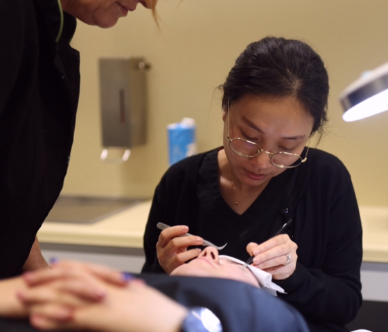 Person applies makeup to student.