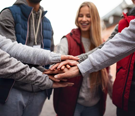 Students place hands on top of each other for encouragement.