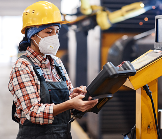 Image of a person wearing overalls and a hard hat working on an autonomous control panel