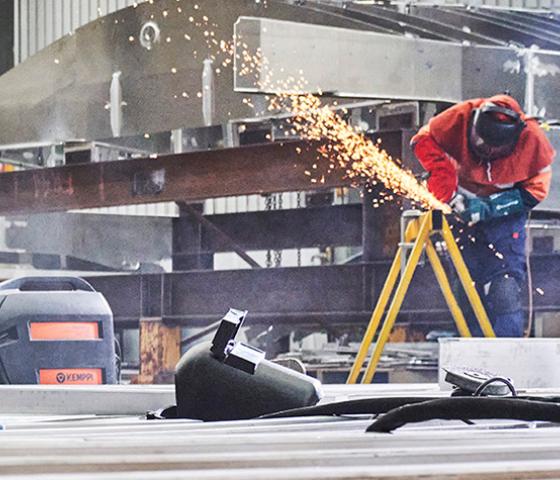 person in workshop grinding working with sheet metal