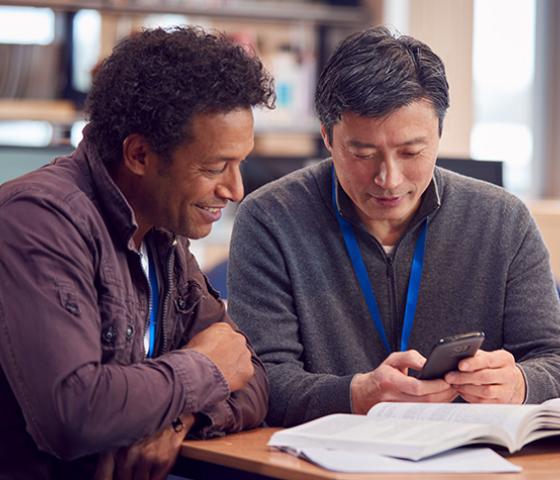 Two people help each other with book work 22484VIC Certificate I in EAL (Access)