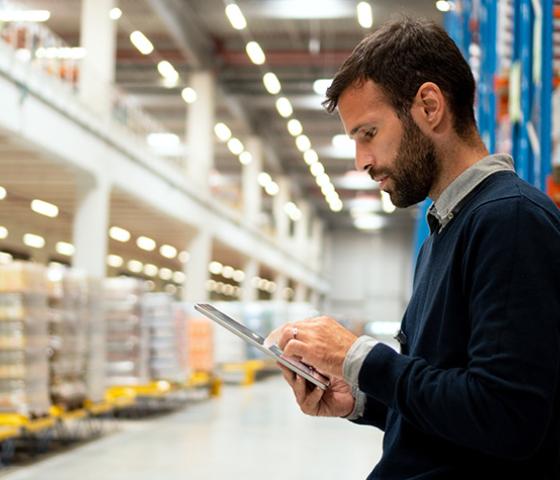 image of a person in warehouse examining computer tablet