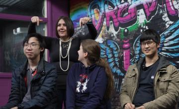 Lecturer April standing behind three seated students in the Immersive Media Studio