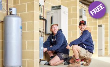 Two plumbing apprentices crouching down doing a repair 