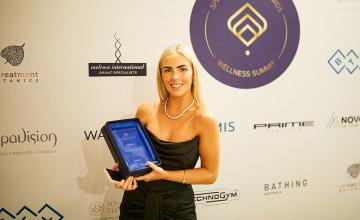Beauty graduate Montana holding her Rising star trophy infront of a media wall